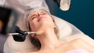 cosmetologist in gloves applies a mask to the client's décolleté and neck with brush skin care